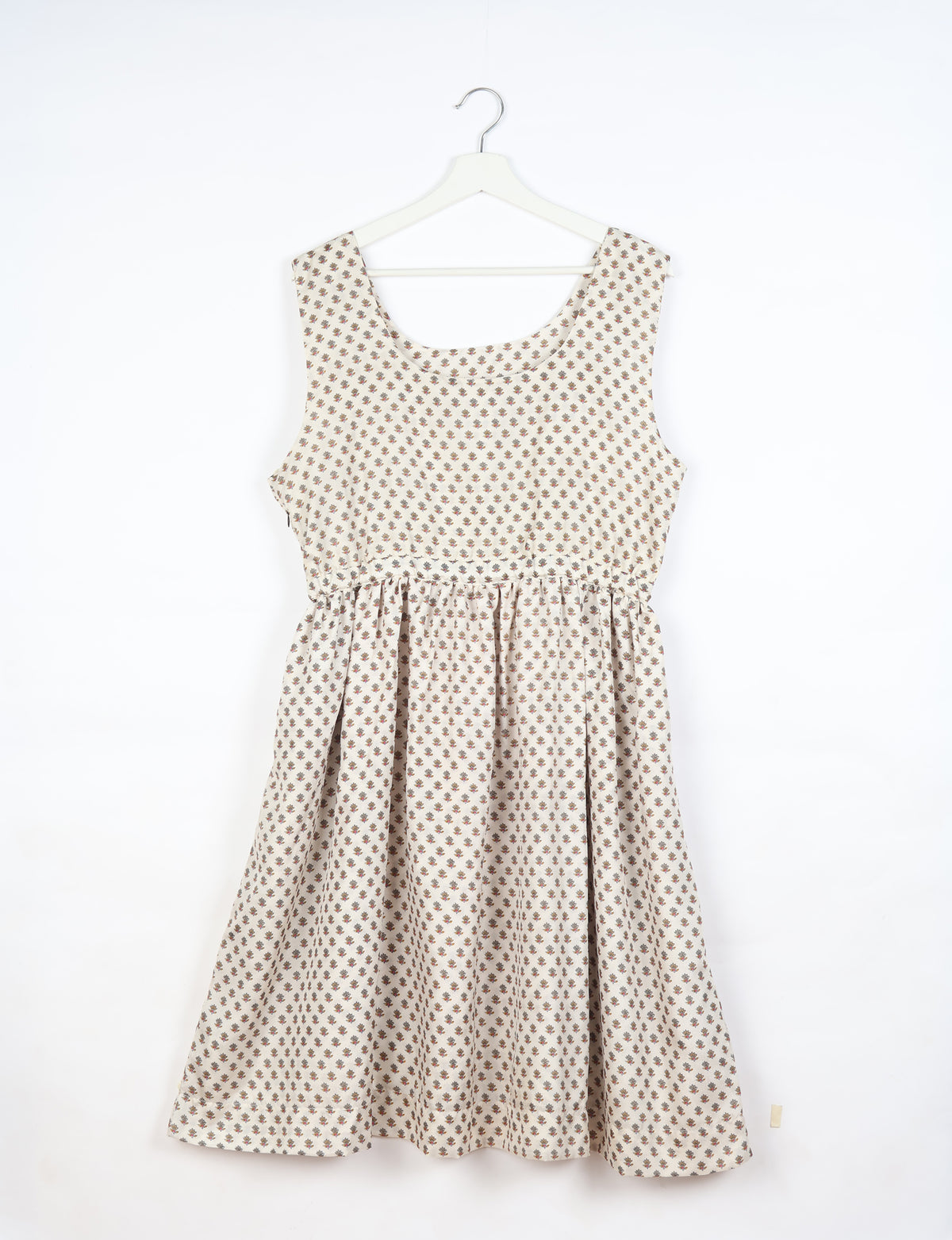 White fit and flare sleeveless dress with small brown floral print, round neckline, hanging on white hanger front view