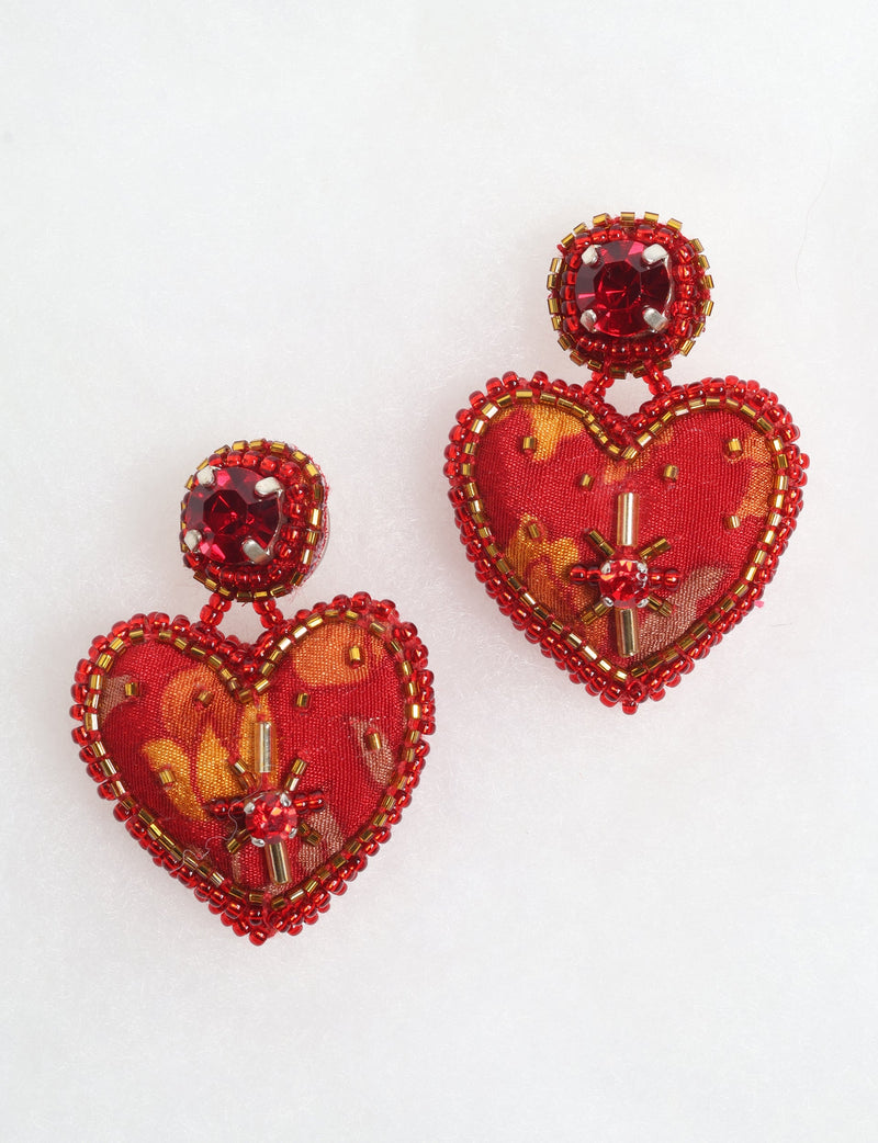 Red heart drop earrings with fabric centers, red and gold bead embellishments, and red gemstone studs, shown on white background