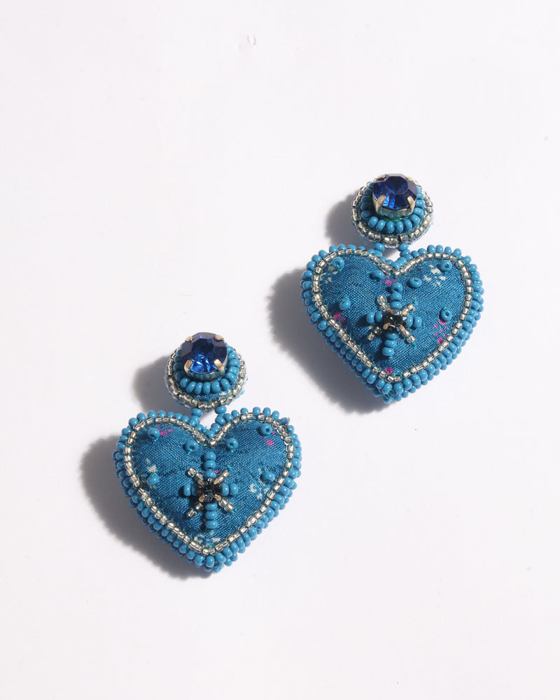 Blue fabric heart drop earrings with blue and silver bead detailing and a blue gemstone stud, shown flat on white background