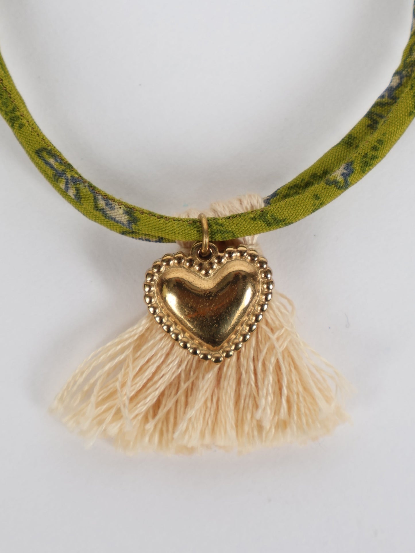 Handmade rope bracelet from recycled sari fabric with gold heart charm and tassels—eco friendly cloth, climate neutral fashion, and upcycled women’s clothing.