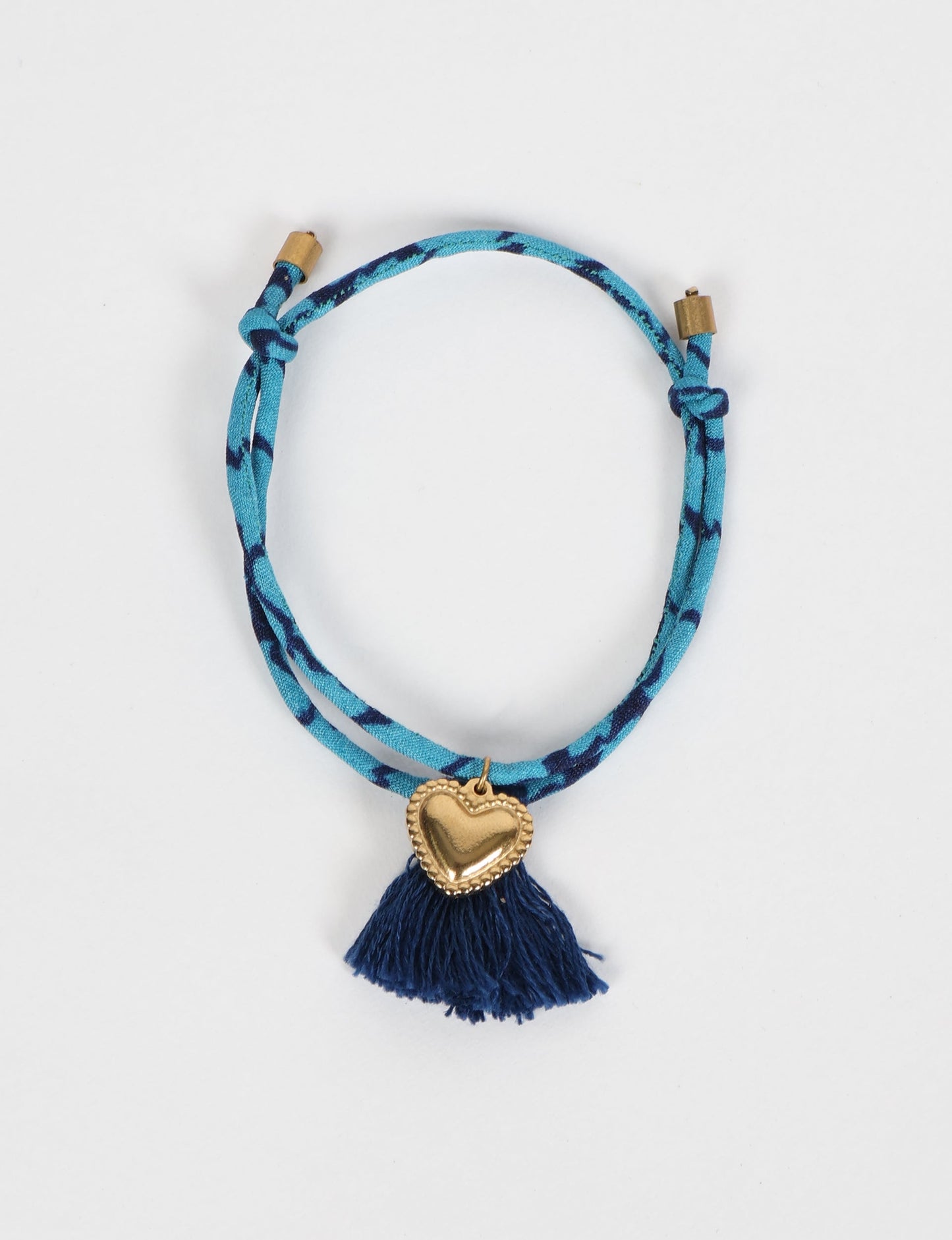 Handmade rope bracelet from recycled sari fabric with gold heart charm and tassels—eco friendly cloth, climate neutral fashion, and upcycled women’s clothing.