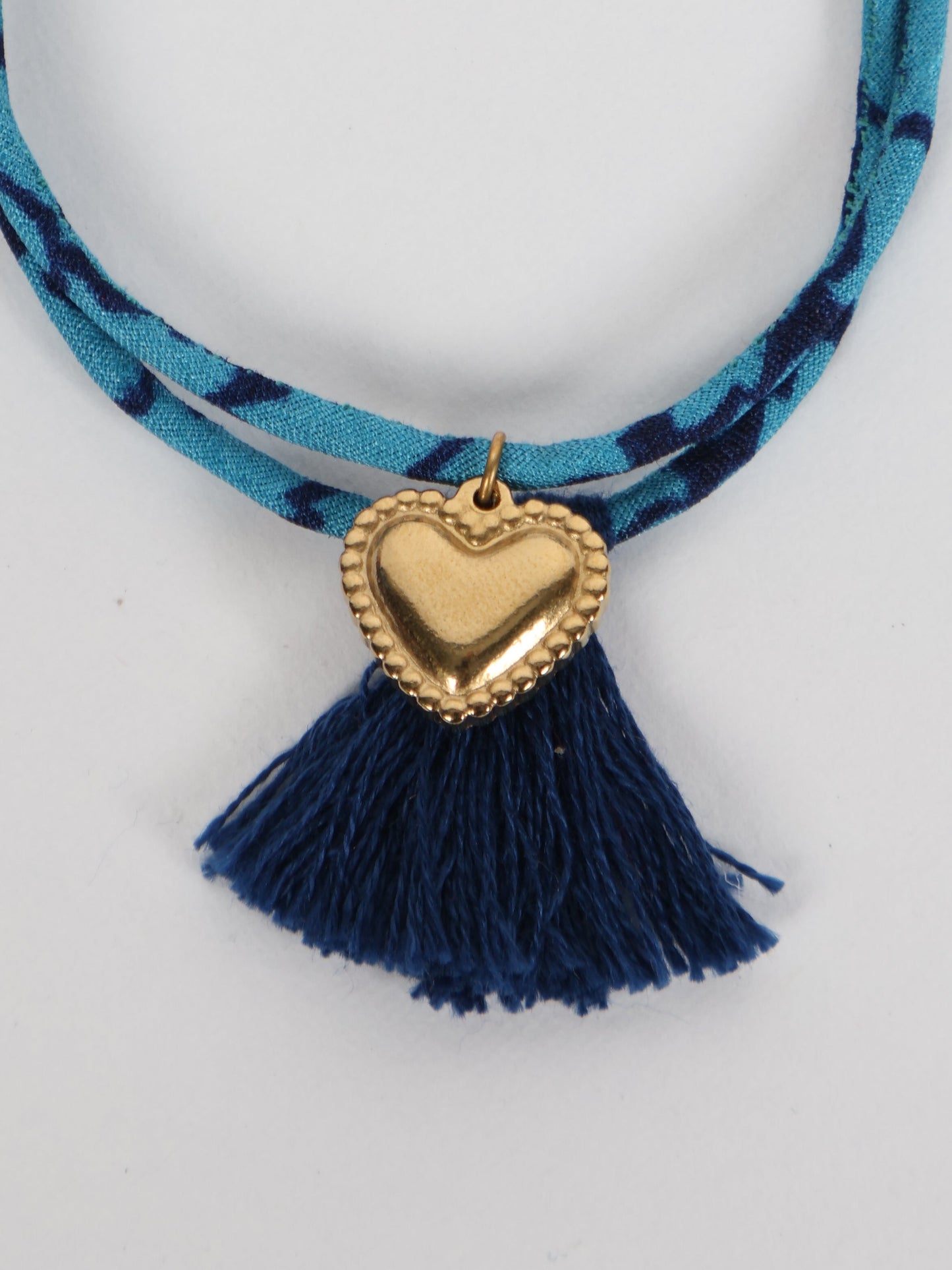 Handmade rope bracelet from recycled sari fabric with gold heart charm and tassels—eco friendly cloth, climate neutral fashion, and upcycled women’s clothing.