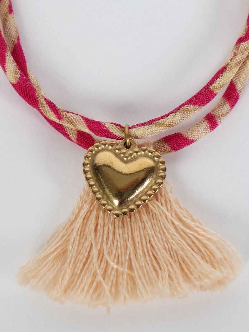 Pink and beige twisted rope bracelet with gold heart charm and light peach tassels, close-up front view on white background