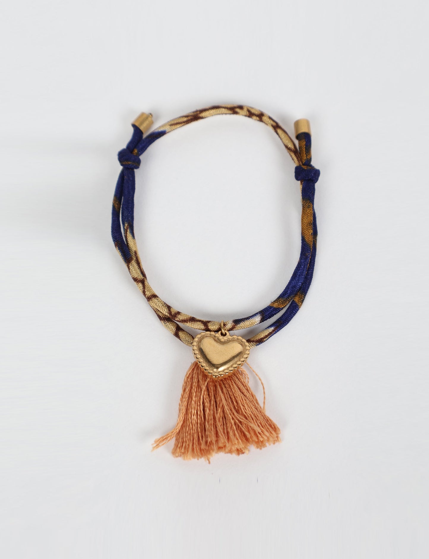 Handmade rope bracelet from recycled sari fabric with gold heart charm and tassels—eco friendly cloth, climate neutral fashion, and upcycled women’s clothing.