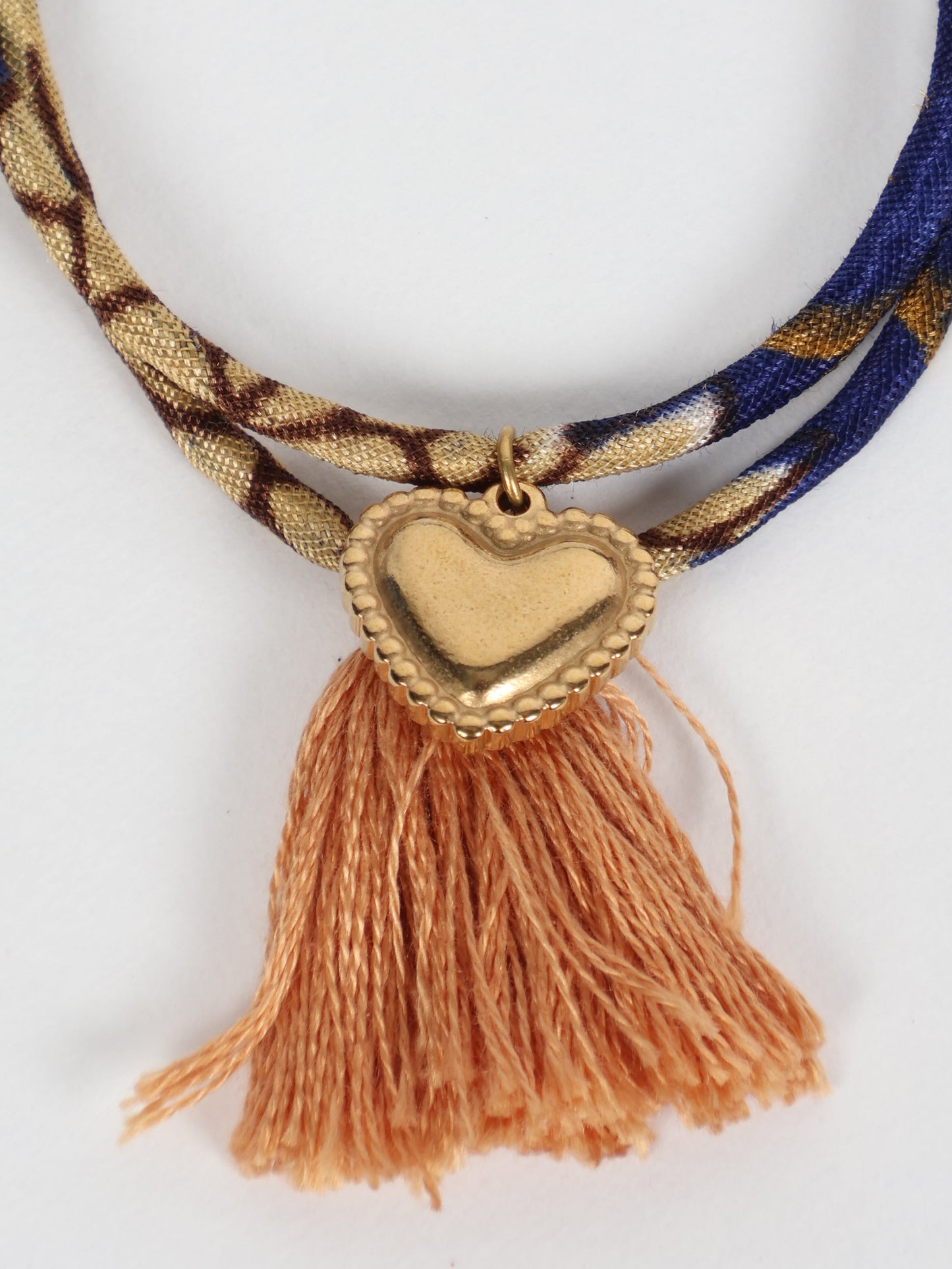 Handmade rope bracelet from recycled sari fabric with gold heart charm and tassels—eco friendly cloth, climate neutral fashion, and upcycled women’s clothing.
