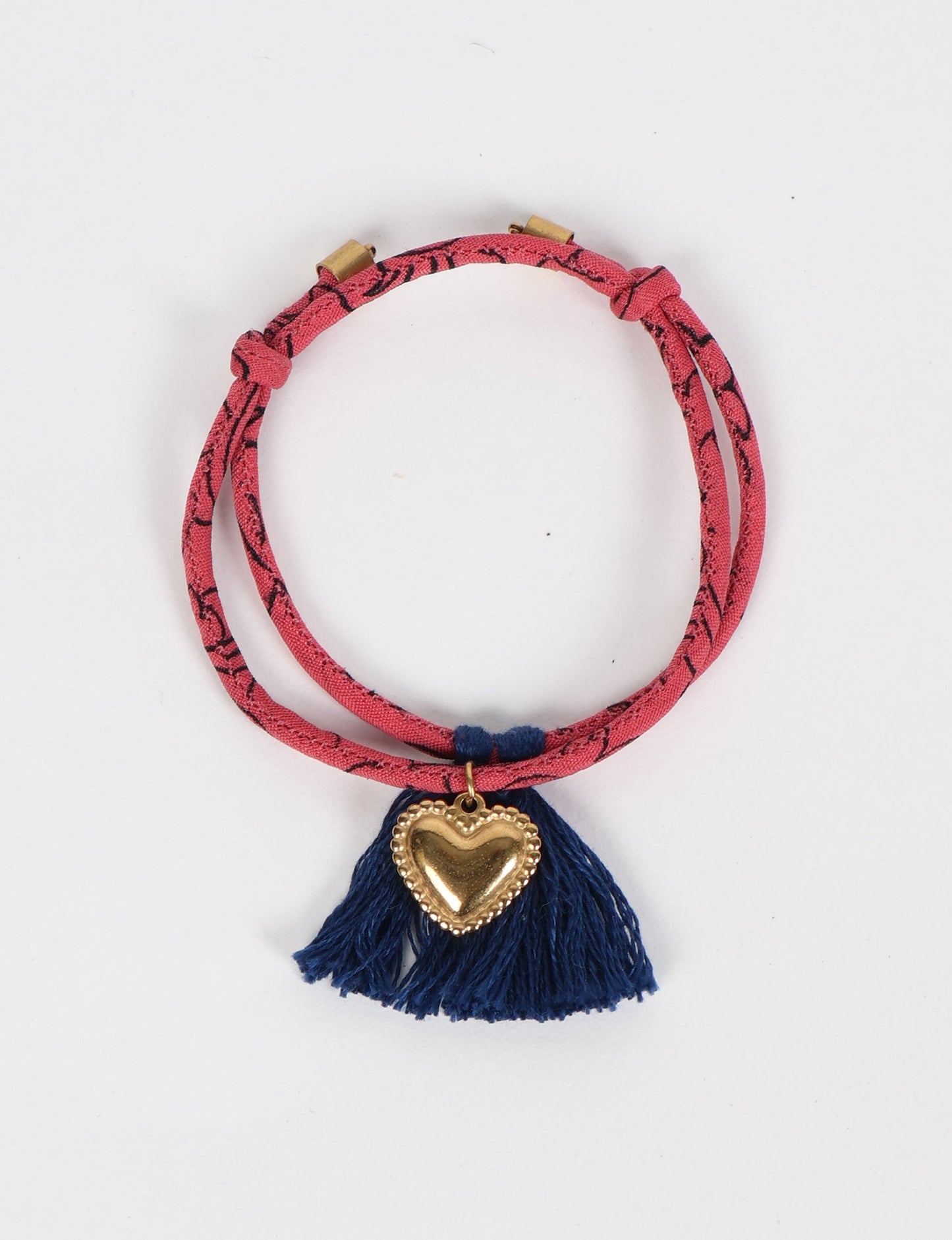 Handmade rope bracelet from recycled sari fabric with gold heart charm and tassels—eco friendly cloth, climate neutral fashion, and upcycled women’s clothing.