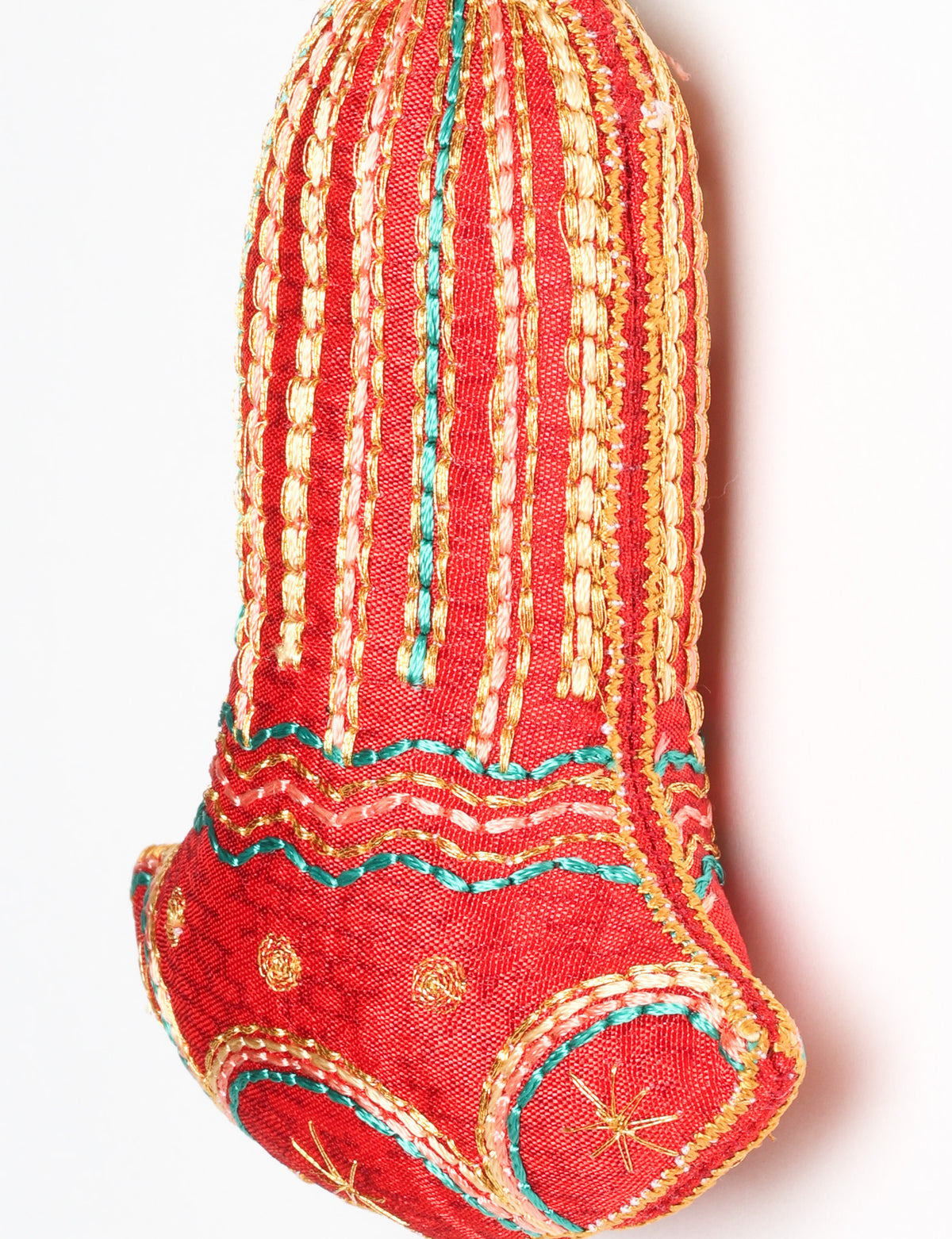 Close-up of a pink fabric bell ornament with gold, teal, and peach embroidered vertical stripes and floral patterns