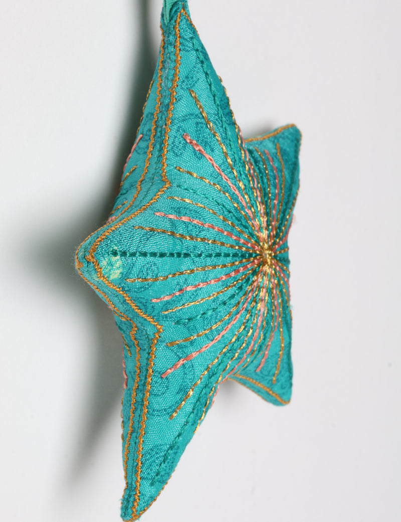 Timeless star ornament made from recycled sari fabric, featuring silk and metallic embroidery, crafted as part of green fashion, recycled clothing design, environmentally friendly clothing practices, and repurposed clothing traditions.