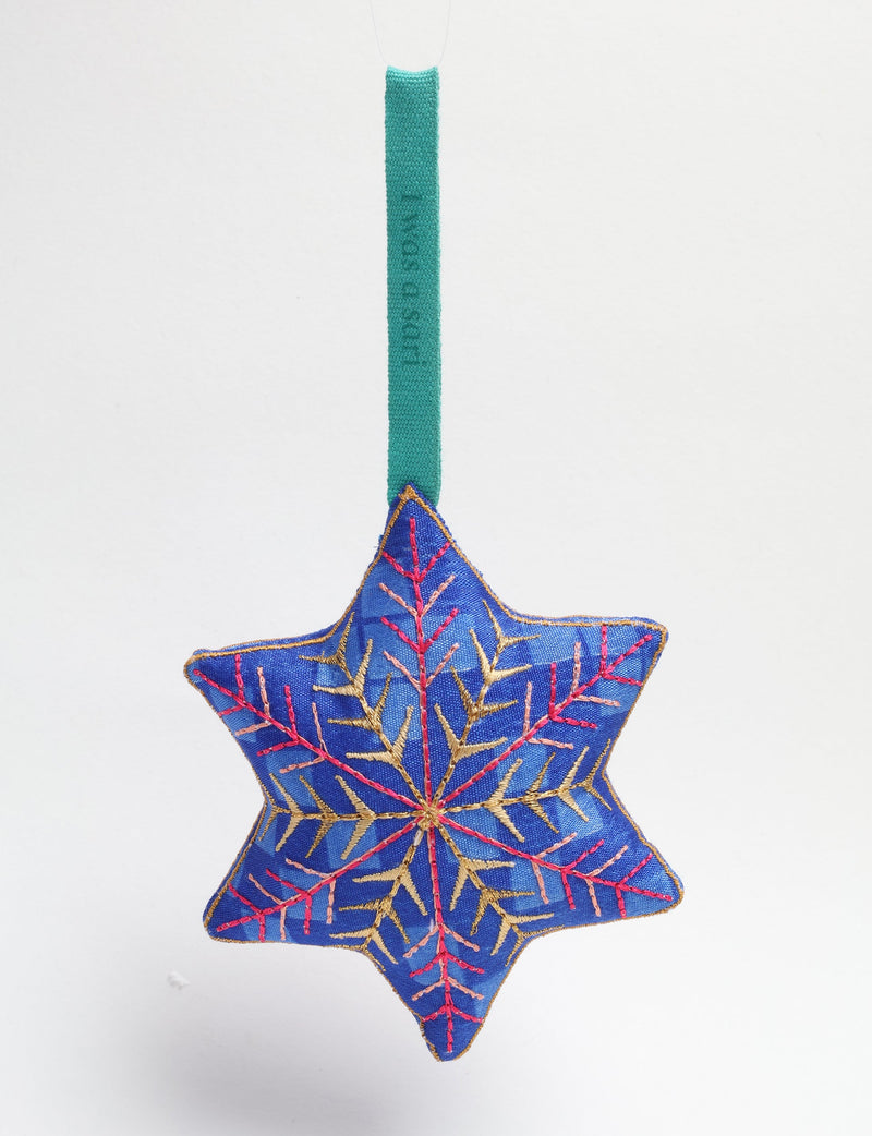 Blue fabric star-shaped ornament with gold and pink embroidered snowflake design hanging by a green loop