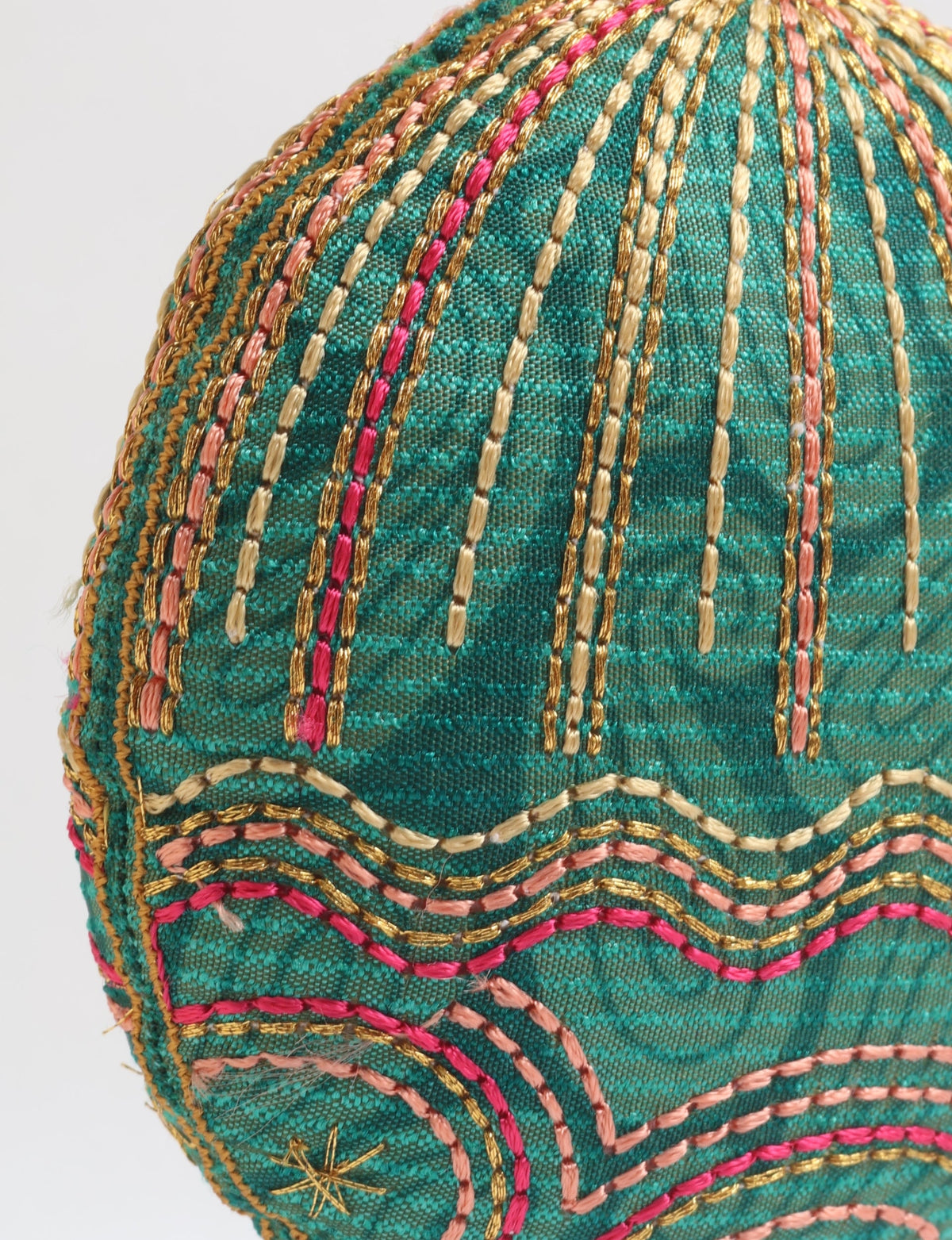 Green paisley fabric ornament with gold, pink, and peach embroidered stripes and star detail, close-up view