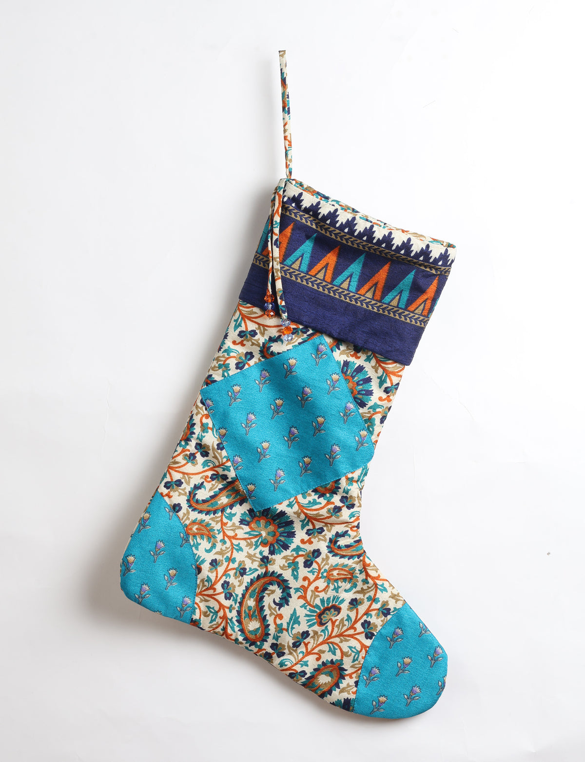 Timeless Christmas stocking made from recycled sari fabric, featuring colorful patchwork, tassel details, and crafted with care in line with circular fashion, upcycling fashion, carbon neutral clothing, and environmentally friendly clothing ideals — a beautiful piece of repurposed clothing and eco clothing for sustainable women’s fashion.