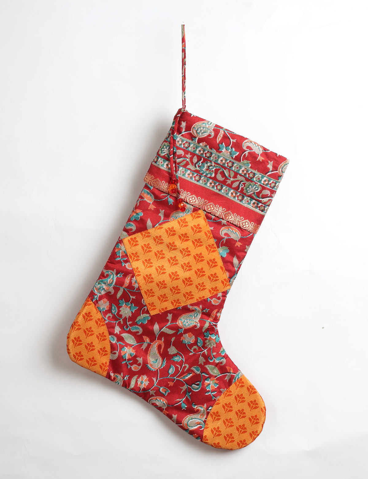 Timeless Christmas stocking made from recycled sari fabric, featuring colorful patchwork, tassel details, and crafted with care in line with circular fashion, upcycling fashion, carbon neutral clothing, and environmentally friendly clothing ideals — a beautiful piece of repurposed clothing and eco clothing for sustainable women’s fashion.