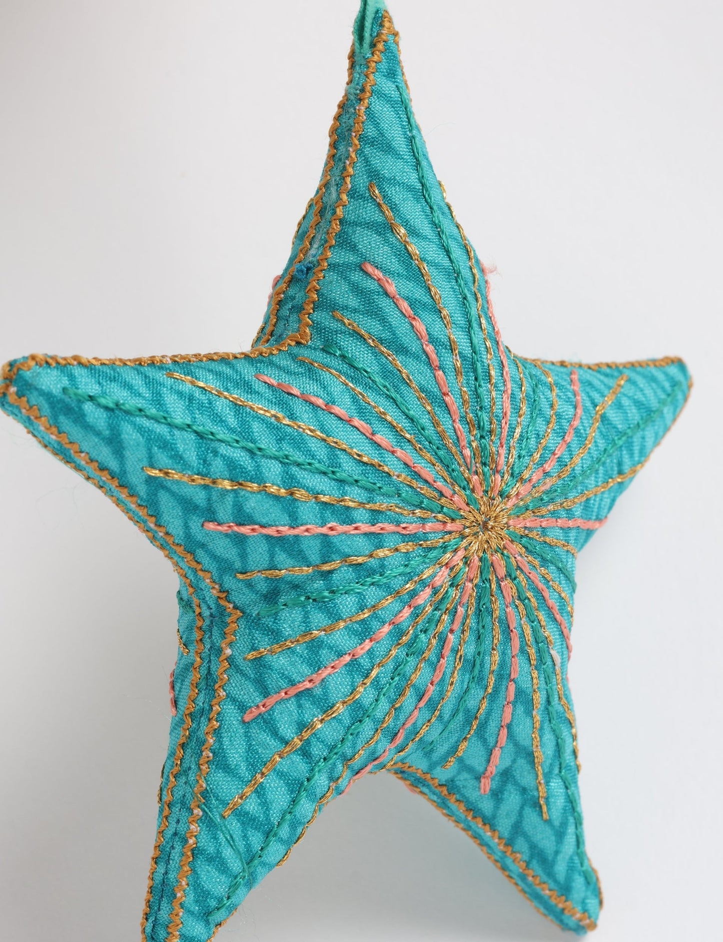 Timeless star ornament made from recycled sari fabric, featuring silk and metallic embroidery, crafted as part of green fashion, recycled clothing design, environmentally friendly clothing practices, and repurposed clothing traditions.