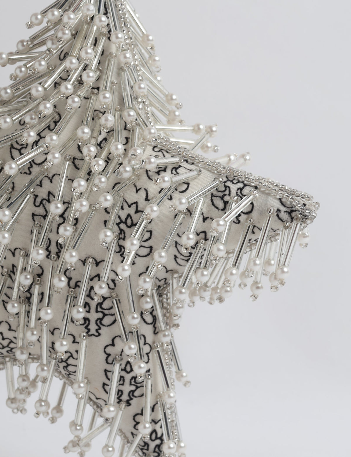 Silver star ornament with white floral fabric, decorated with pearl and silver bead embellishments, close-up view