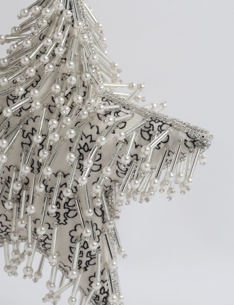 Silver star ornament with white floral fabric, decorated with pearl and silver bead embellishments, close-up view