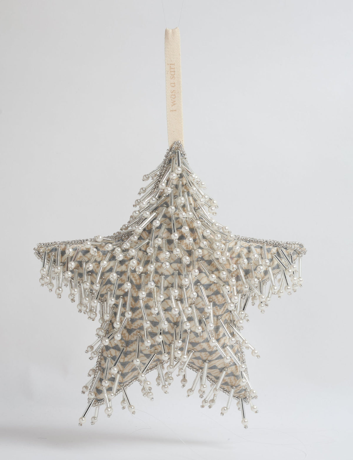 Beige star ornament with micro pattern, decorated with silver beads and pearls, hanging by a beige fabric loop