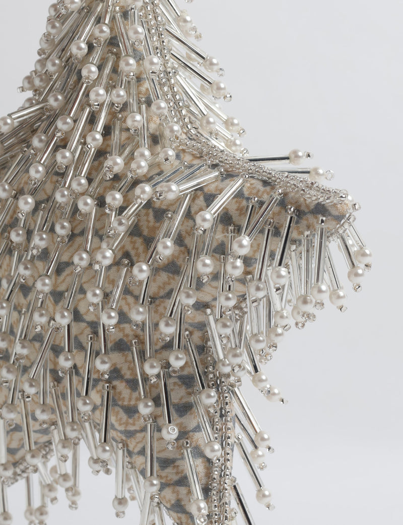 Silver star ornament with beige patterned fabric base, decorated with clear tubes and pearl-like beads, close-up view