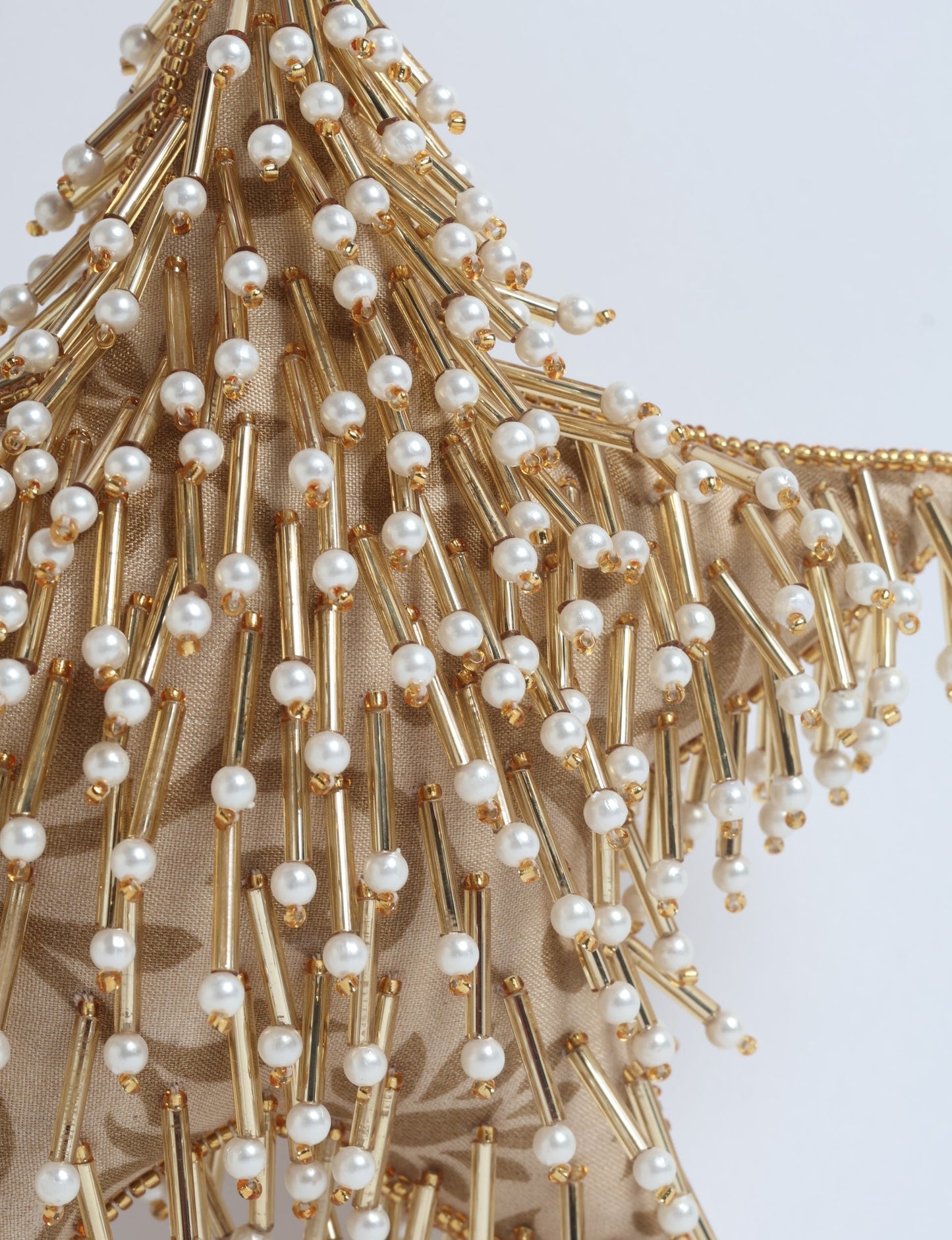 Gold colored star ornament made from ivory and gold preloved saris, filled with organic cotton and decorated with silver hand embroidery, representing upcycled clothing, green fashion, fair trade fashion, recycled material clothing, repurposed clothing, climate neutral clothing, eco clothing, second hand clothing, recycled sustainable fashion, and sustainable women’s clothing.