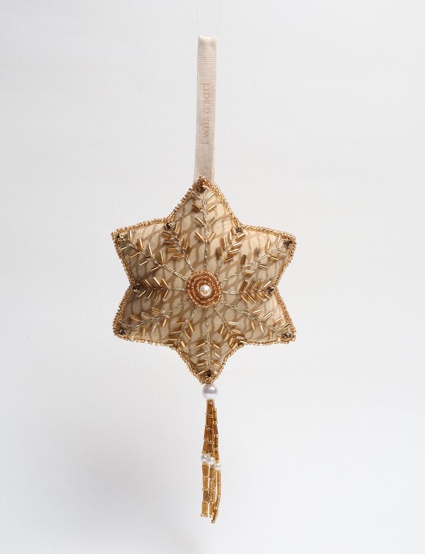 Gold snowflake ornament made from recycled sari fabric, featuring sequins, pearls, and glass beads. This ethically crafted piece aligns with green fashion, fair trade fashion, and sustainable women’s clothing, promoting zero waste clothing and products made from textile waste.