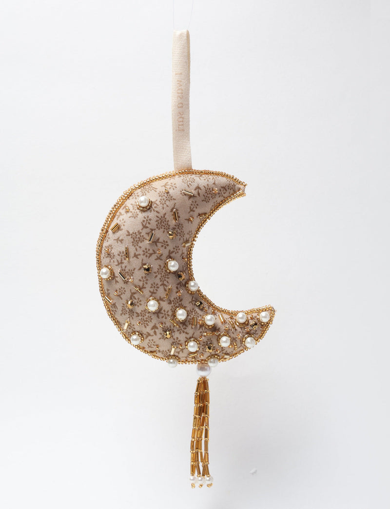Gold crescent moon ornament with floral fabric, pearl and gold bead embellishments, hanging loop, and beaded tassel detail