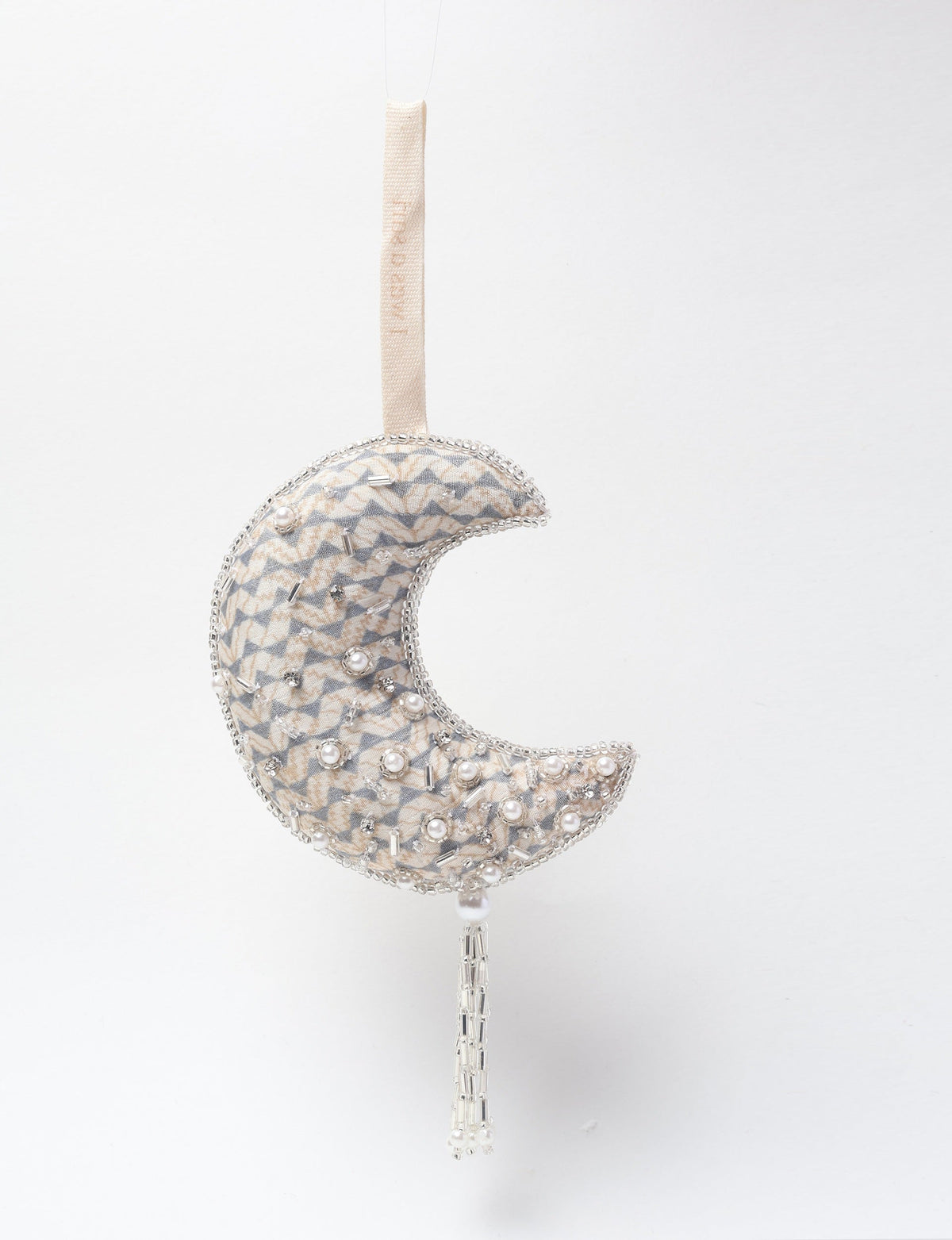 Silver crescent moon ornament with beige and gray fabric, pearl and bead embellishments, hanging by a beige loop strap