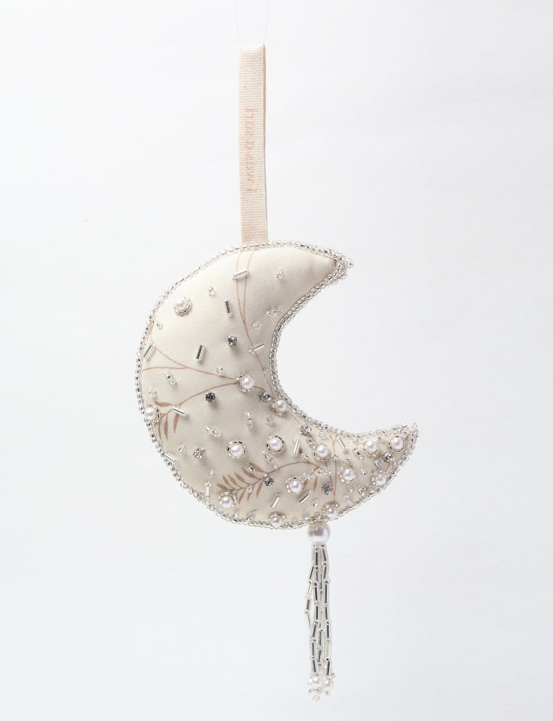 Silver crescent moon ornament with pearl and bead embellishments, hanging by a fabric loop with beaded tassel