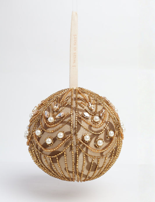 Gold colored ball ornament handcrafted from recycled sari products and repurposed clothing, featuring silver hand embroidery, pearls, sequins, and beads. Made through circular fashion and sustainable women’s clothing processes, this piece represents eco friendly fashion, carbon neutral clothing, and environmentally friendly clothing inspired by conscious clothing principles.