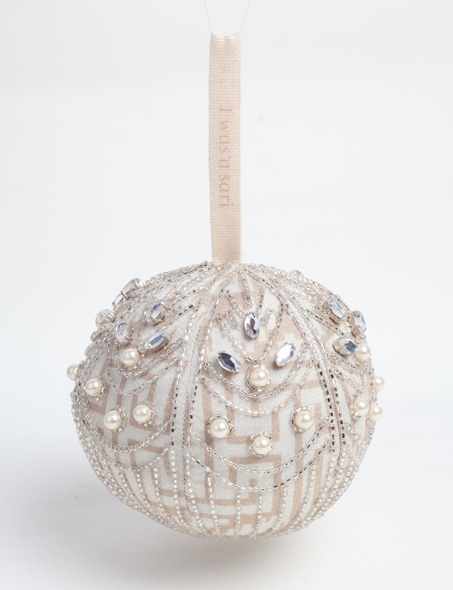 Silver colored ball ornament handcrafted from recycled sari fabric with silver embroidery and beads, representing upcycled clothing, sustainable women’s clothing, green fashion, slow fashion, and eco friendly fashion made from recycled materials.