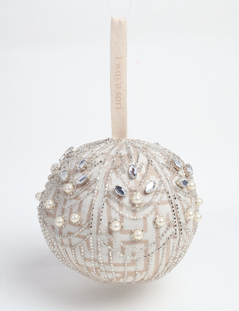 Silver ball ornament with pearl and crystal bead embellishments and a beige hanging loop with faint text visible