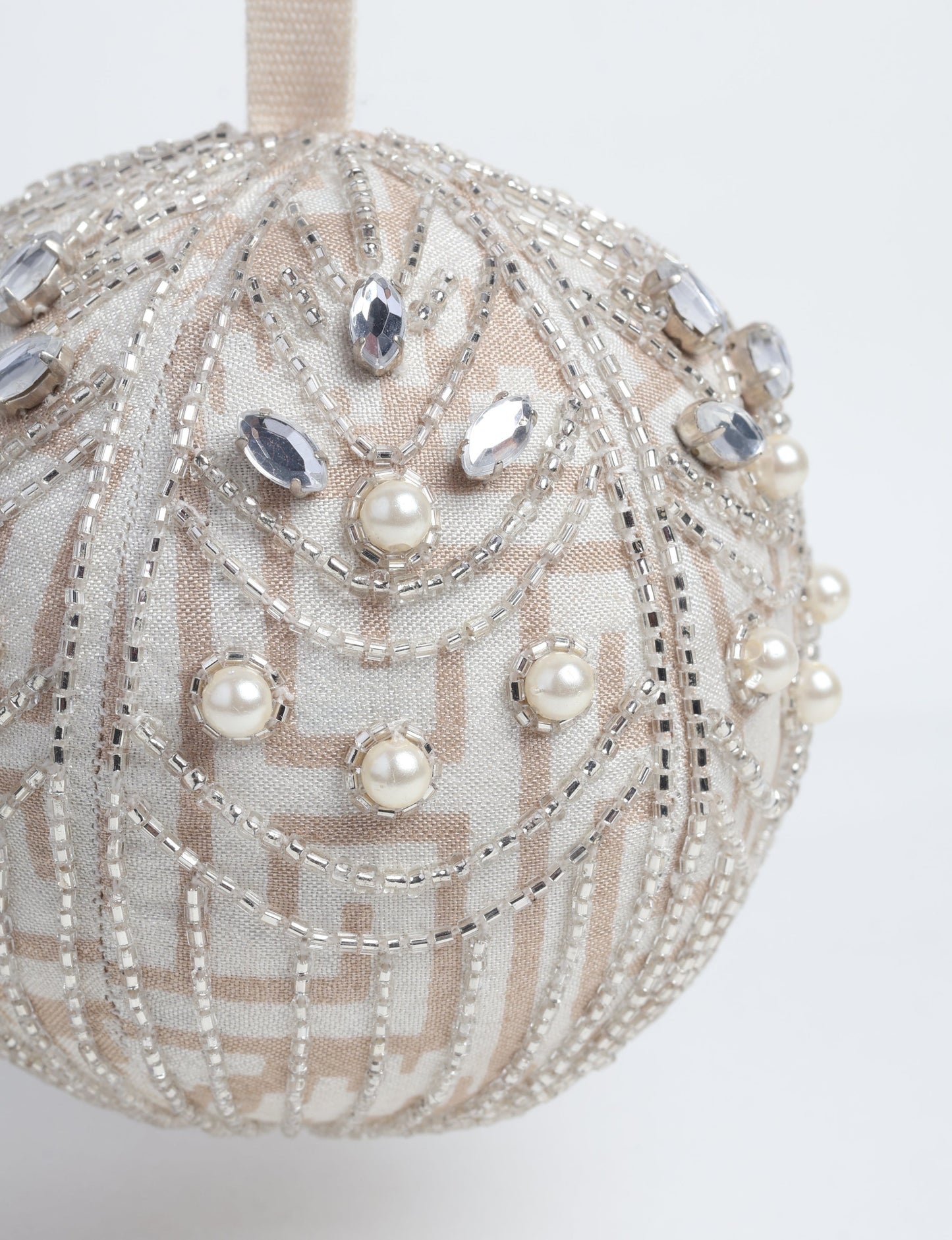 Silver colored ball ornament handcrafted from recycled sari fabric with silver embroidery and beads, representing upcycled clothing, sustainable women’s clothing, green fashion, slow fashion, and eco friendly fashion made from recycled materials.