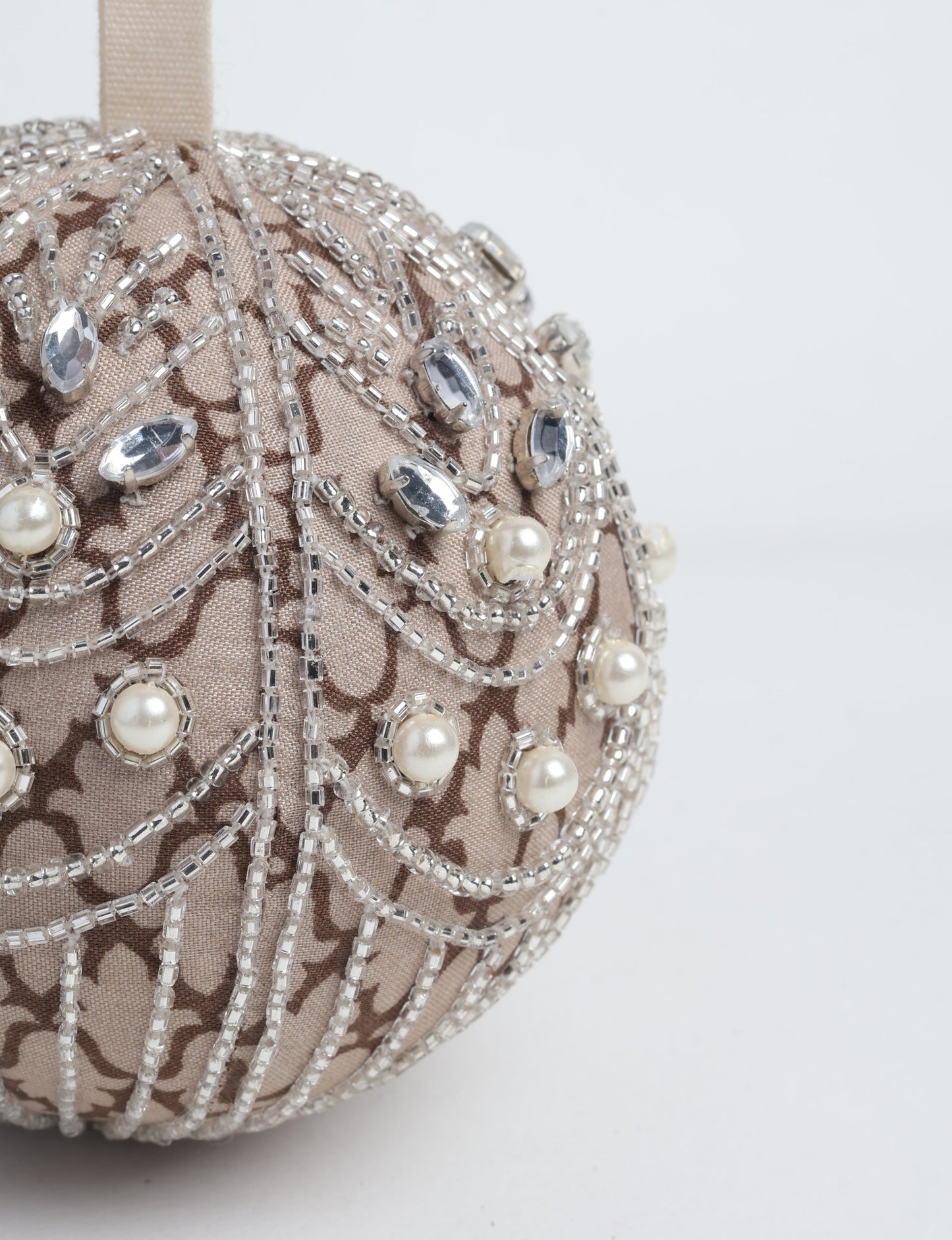 Silver colored ball ornament handcrafted from recycled sari fabric with silver embroidery and beads, representing upcycled clothing, sustainable women’s clothing, green fashion, slow fashion, and eco friendly fashion made from recycled materials.