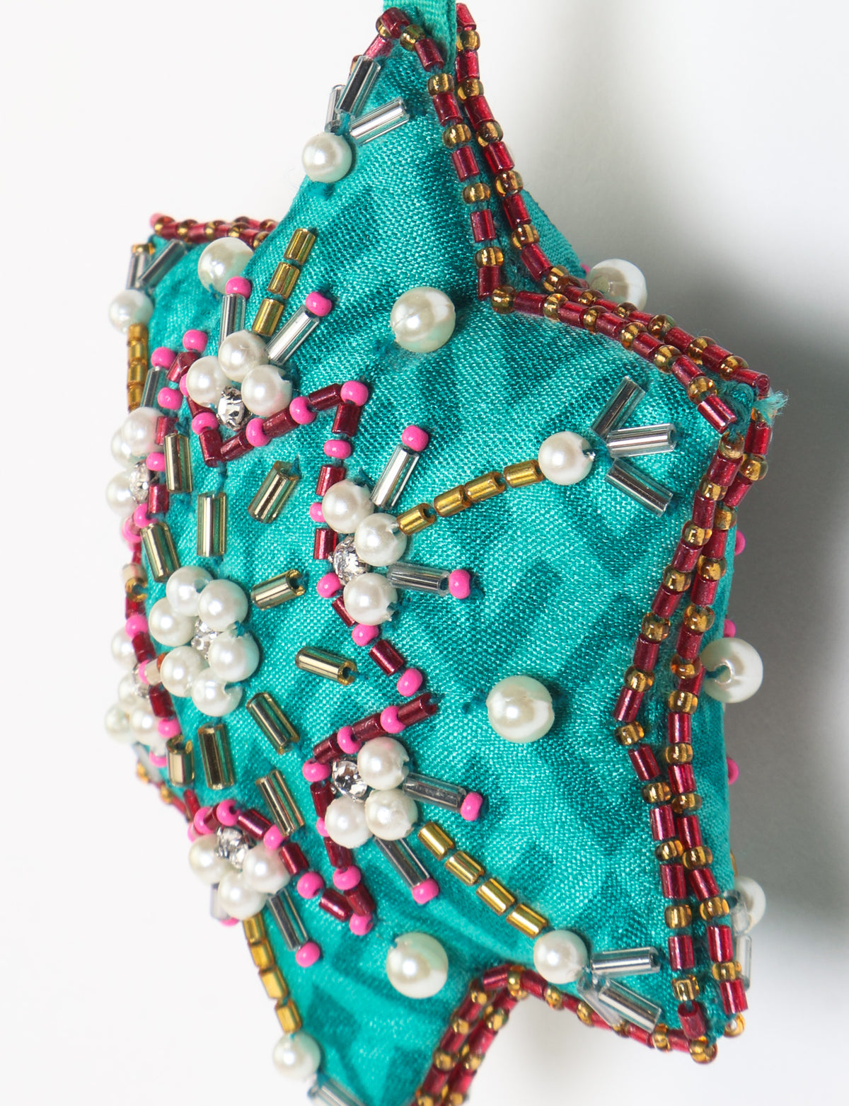 Teal fabric star-shaped snowflake ornament with bead and pearl embellishments, hanging by a teal fabric loop