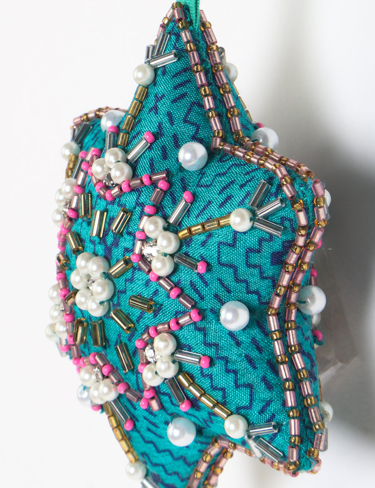Teal fabric star-shaped snowflake ornament with bead and pearl embellishments, hanging by a teal fabric loop