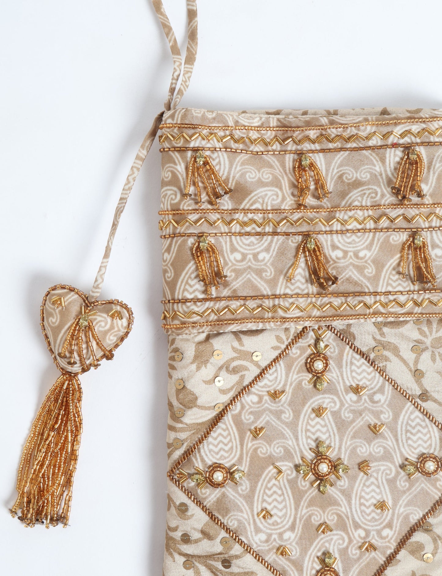 Ivory and cream upcycled sari Christmas stocking with gold hand embroidery, patchwork detailing, and a beaded heart charm tassel — crafted from recycled materials and inspired by circular, fair trade, and eco clothing fashion.