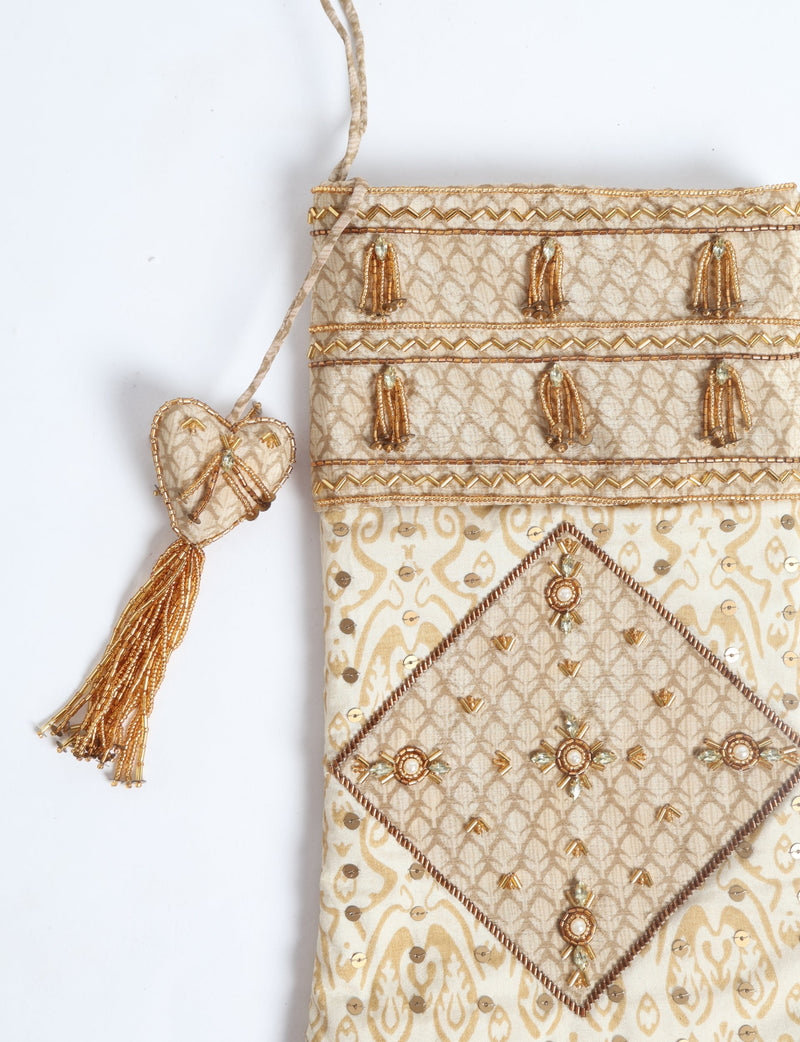 Beige patchwork Christmas stocking with gold bead embroidery, sequins, tassel, and heart-shaped hanging ornament, flat lay view