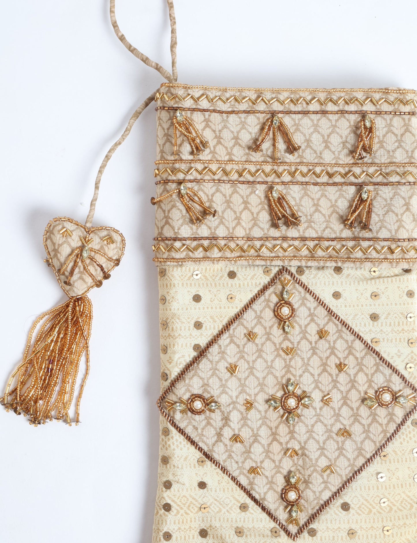 Ivory and cream upcycled sari Christmas stocking with gold hand embroidery, patchwork detailing, and a beaded heart charm tassel — crafted from recycled materials and inspired by circular, fair trade, and eco clothing fashion.