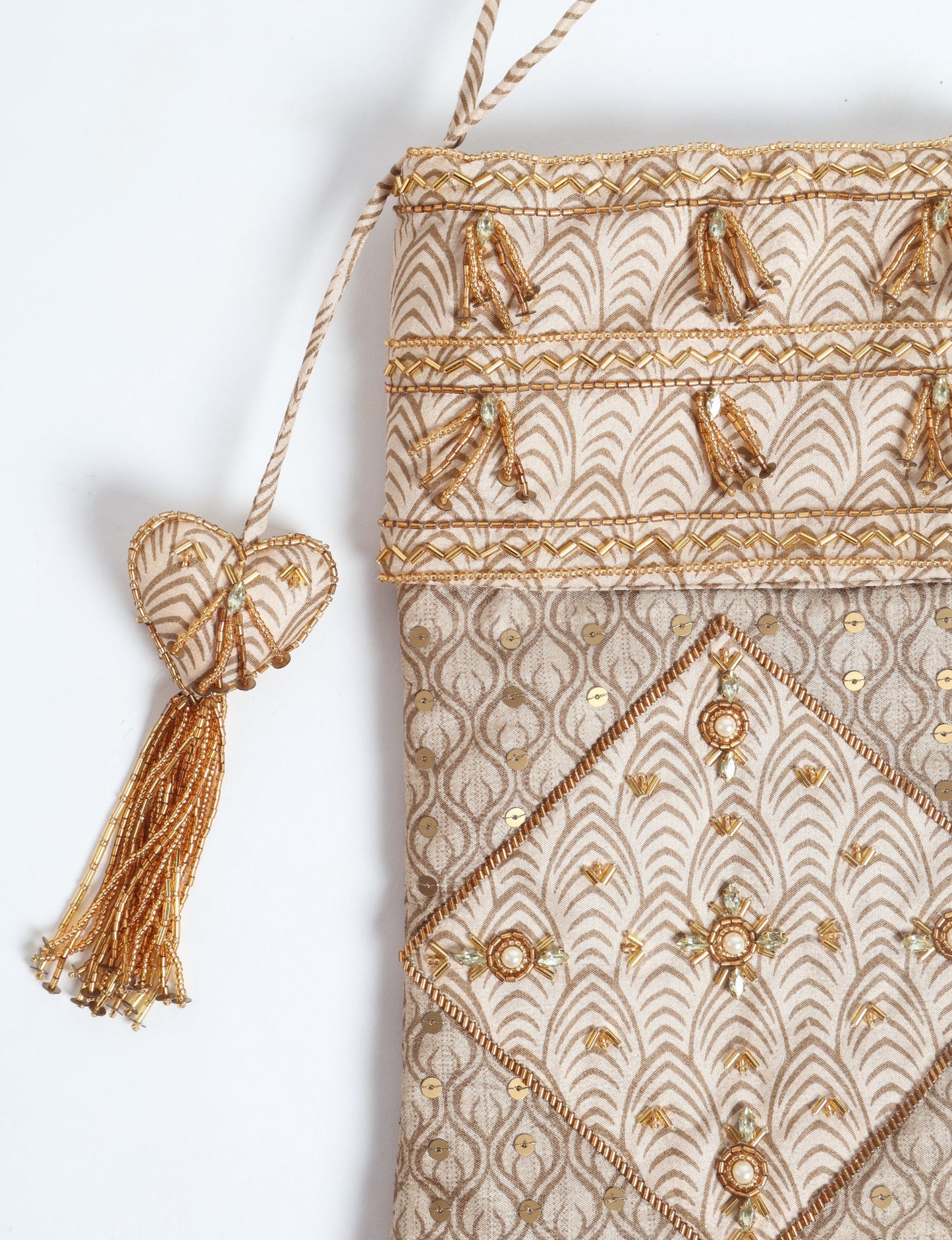 Ivory and cream upcycled sari Christmas stocking with gold hand embroidery, patchwork detailing, and a beaded heart charm tassel — crafted from recycled materials and inspired by circular, fair trade, and eco clothing fashion.