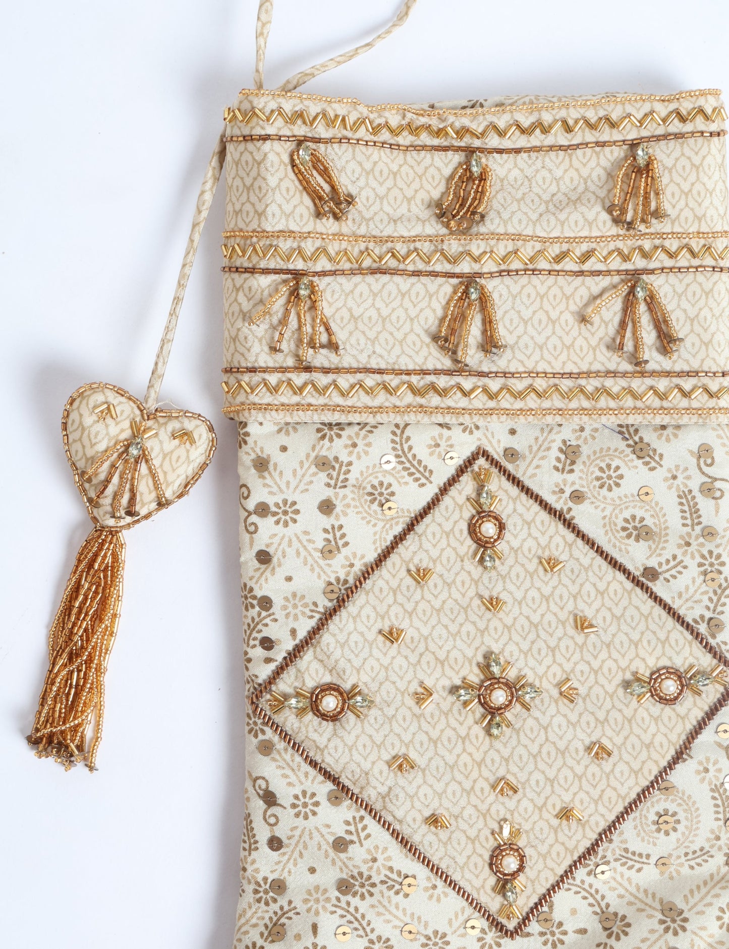 Ivory and cream upcycled sari Christmas stocking with gold hand embroidery, patchwork detailing, and a beaded heart charm tassel — crafted from recycled materials and inspired by circular, fair trade, and eco clothing fashion.