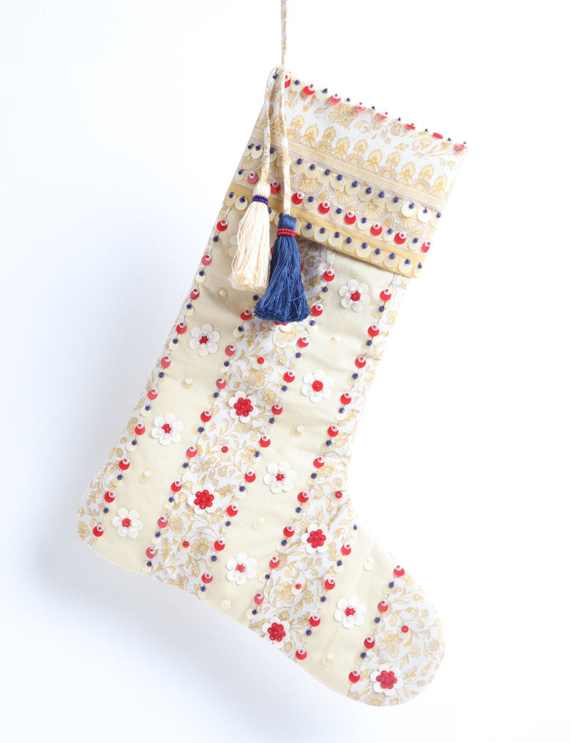 Cream and gold floral Christmas stocking with red, white, and blue sequins and two hanging tassels, front view hanging