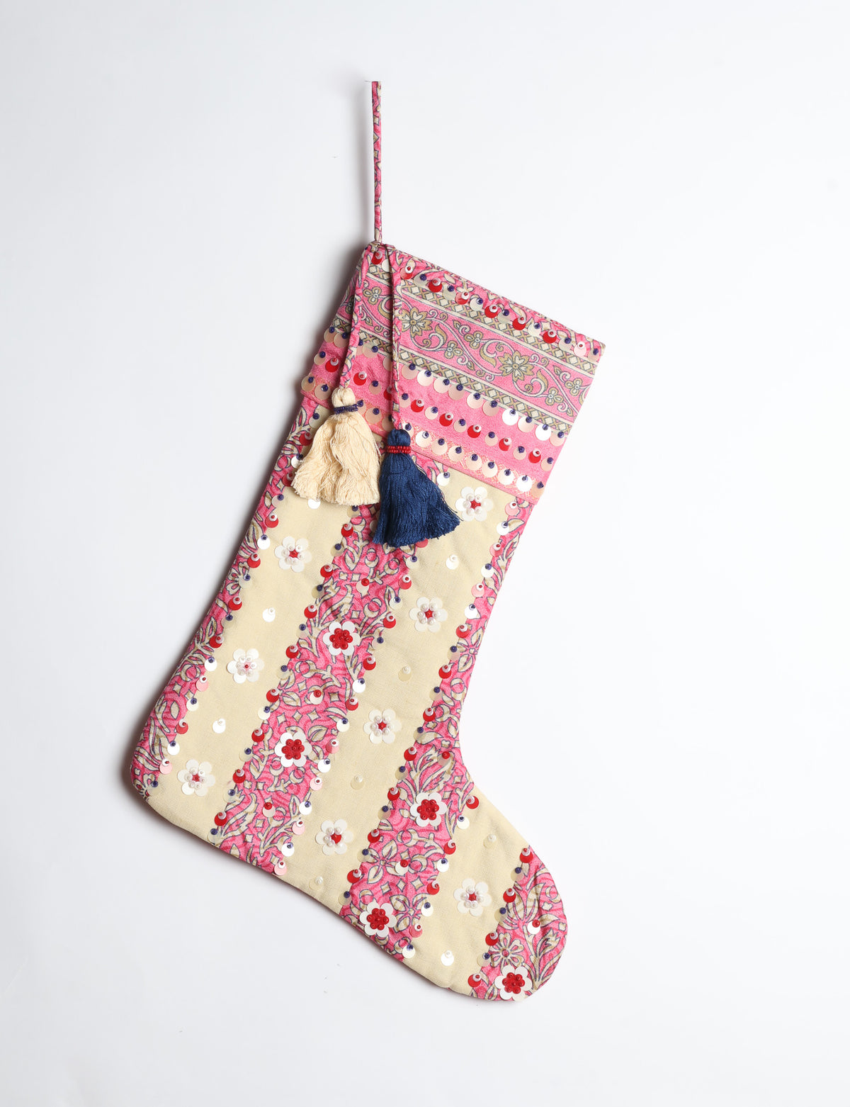 Blue and cream Christmas stocking with floral patterns, sequins, and two hanging tassels, shown hanging against white background