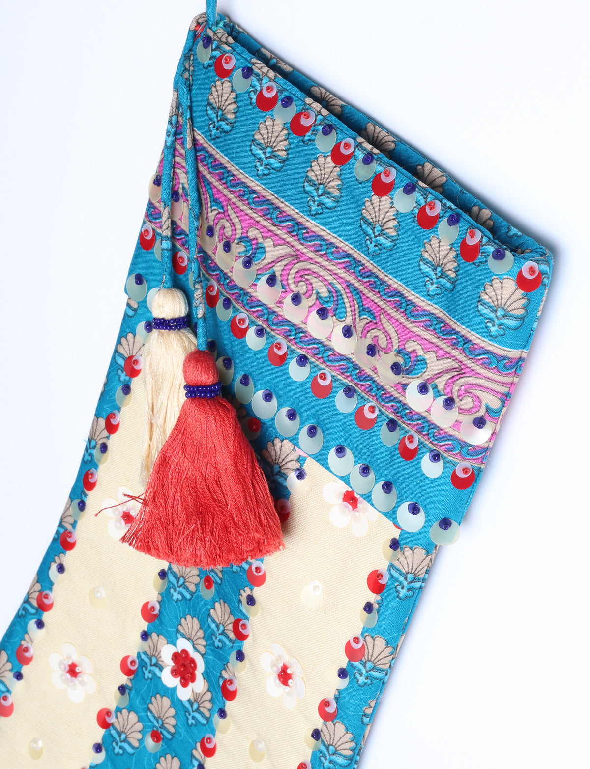 Blue and cream flower-patterned Christmas stocking with red, white, and purple sequins and two tassels hanging from the top loop