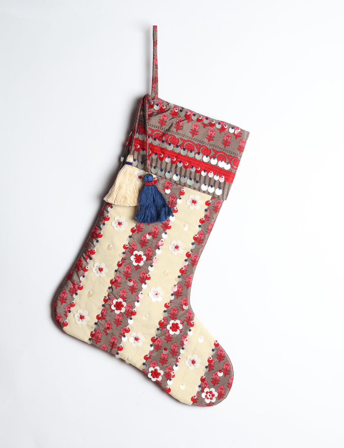 Blue and cream Christmas stocking with floral patterns, sequins, and two hanging tassels, shown hanging against white background