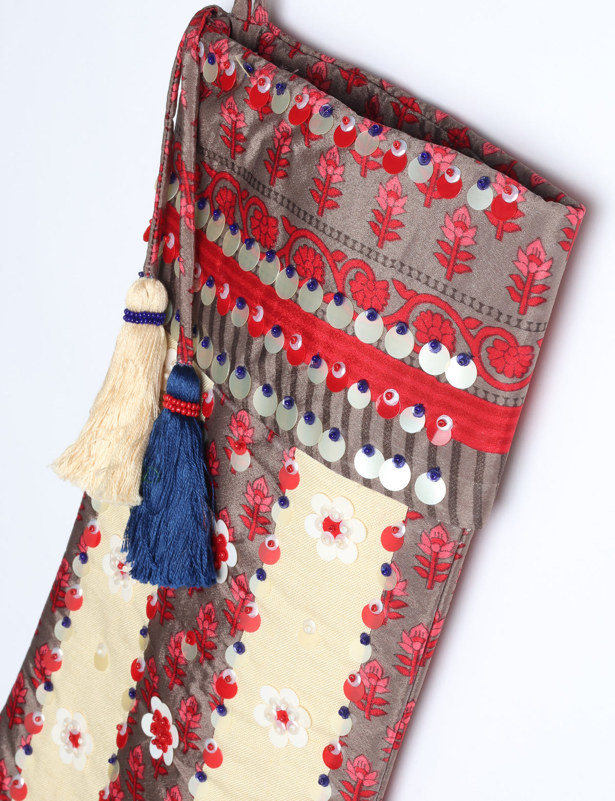 Blue and cream flower-patterned Christmas stocking with red, white, and purple sequins and two tassels hanging from the top loop