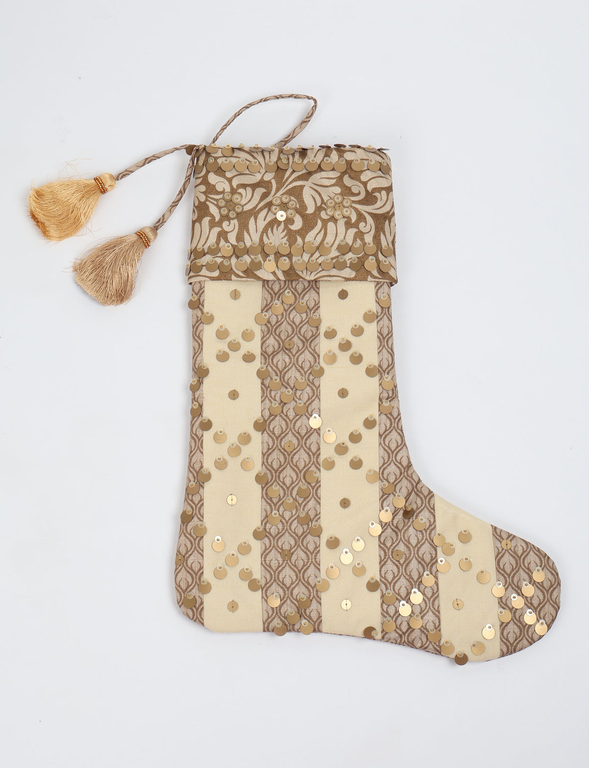 Beige and brown striped Christmas stocking with floral pattern, gold sequins, and two gold tassels on hanging loop, flat lay