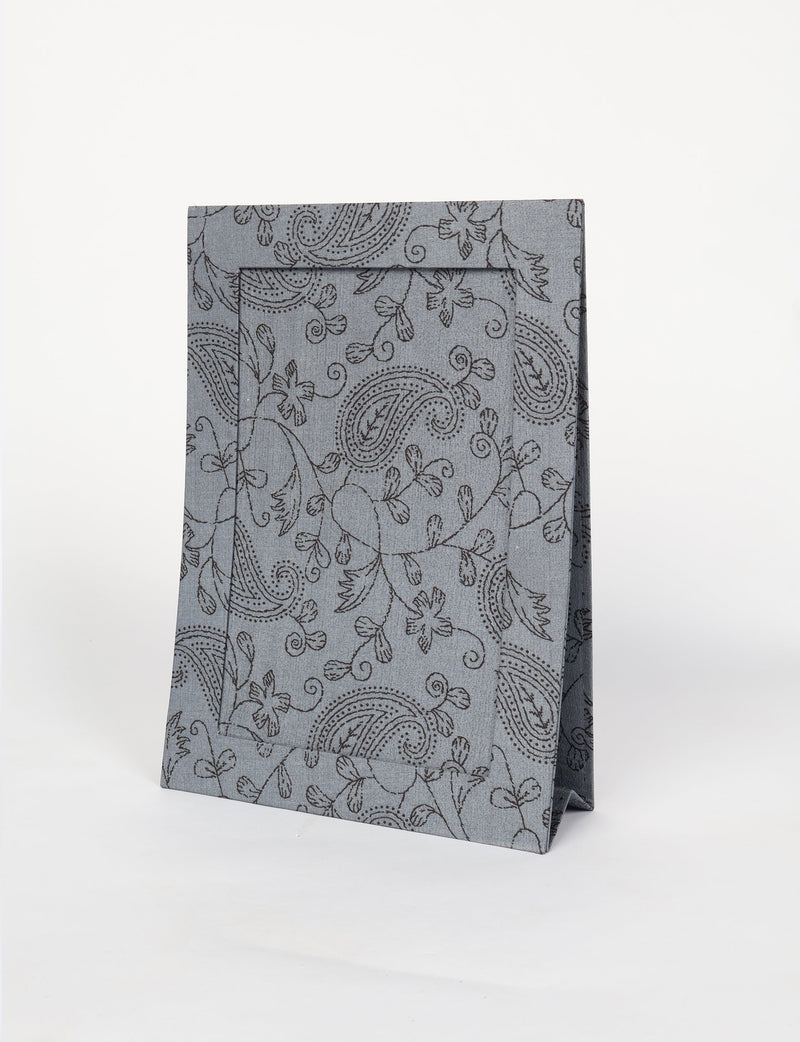 Gray fabric photo frame with black paisley and floral pattern, standing upright on a white background