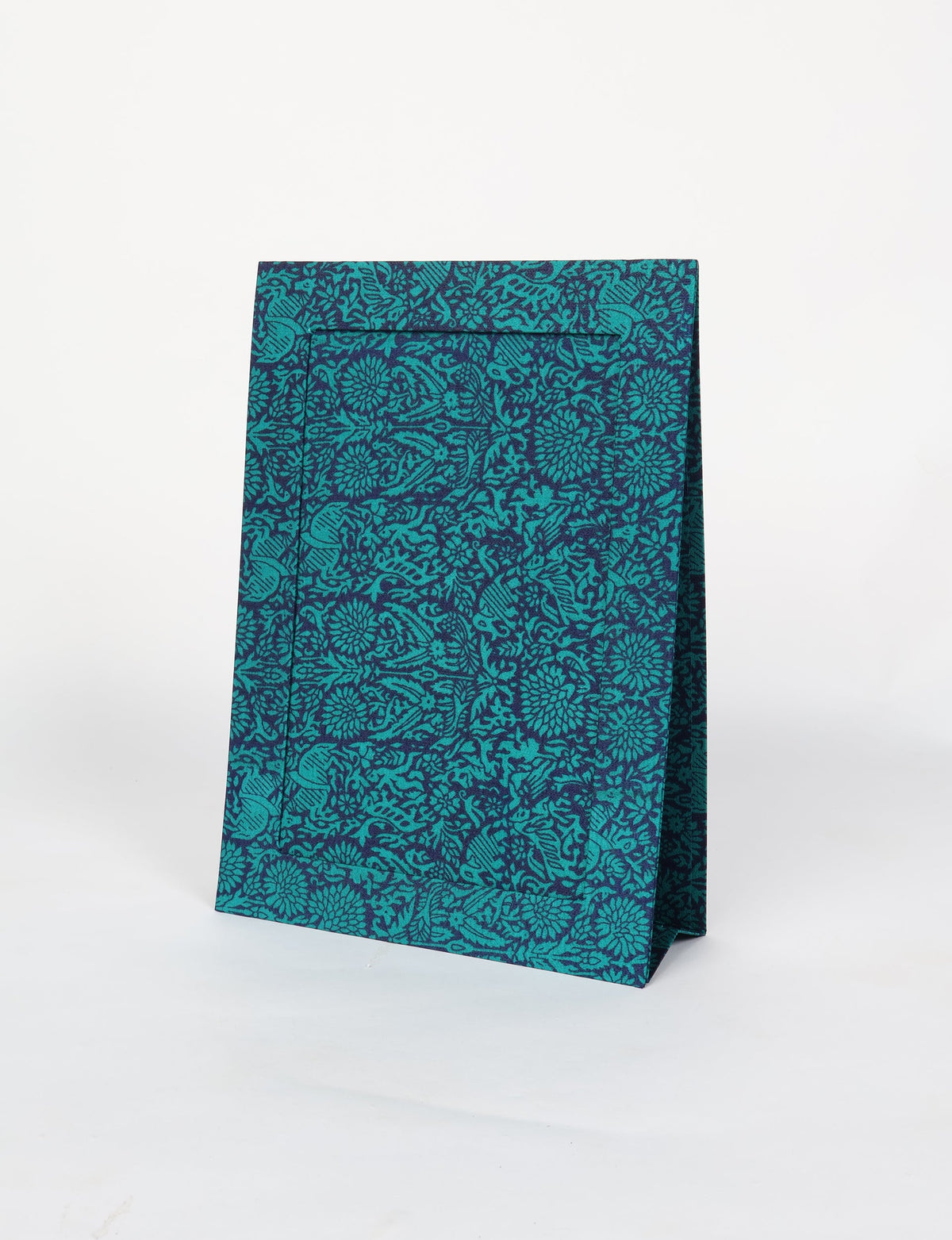Blue and teal fabric gift bag with intricate floral and animal pattern, standing upright on white background