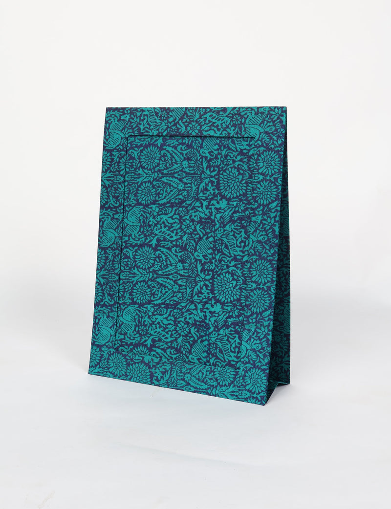 Blue and teal fabric gift bag with intricate floral and animal pattern, standing upright on white background
