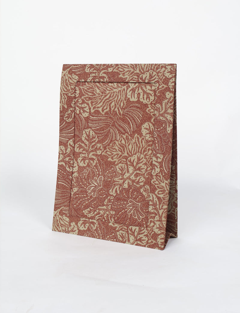 Brown tropical patterned photo frame standing upright with a textured leaf design, shown on a white background