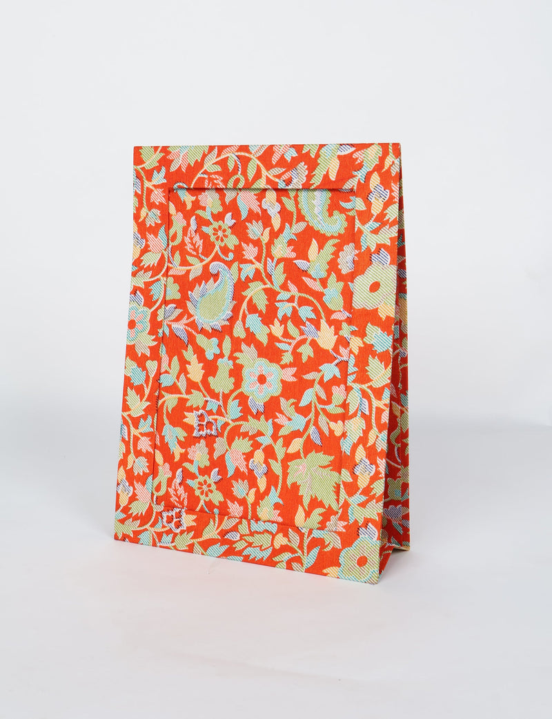 Brown tropical patterned photo frame with floral and leaf designs, standing upright on a white background