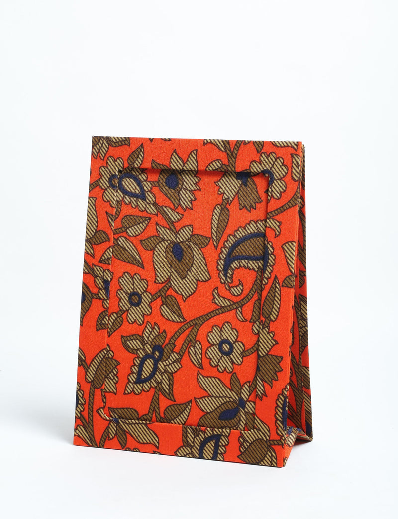 Orange tropical patterned fabric photo frame standing upright with floral and leaf designs in brown and navy blue